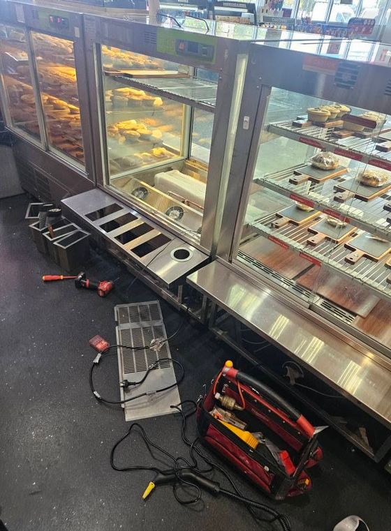 Bakery display cases opened up for refrigeration repair with covers off