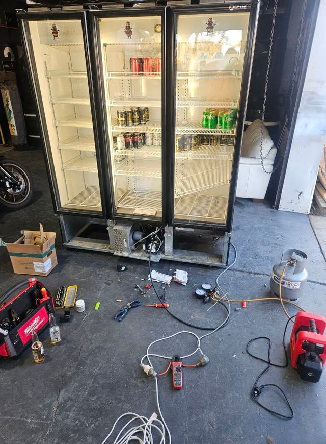 Triple glass door commercial drink fridge under repair with clamp meter and gauges connected