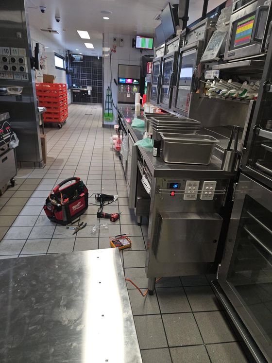 Refrigeration service in progress in a fast food restaurant kitchen, tool bag and gauges on the floor