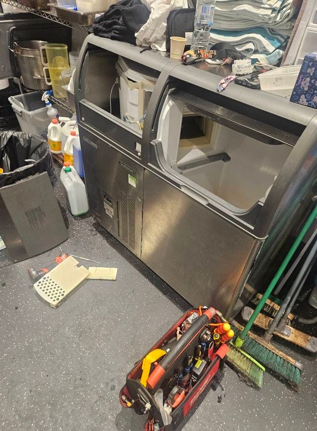 Commercial ice machine opened up for service in a restaurant kitchen
