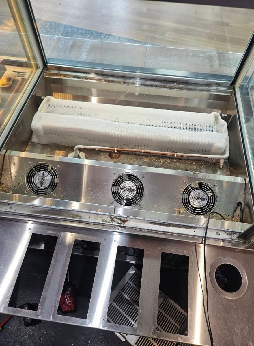 Evaporator coil completely encased in ice inside a display fridge, a classic defrost system failure