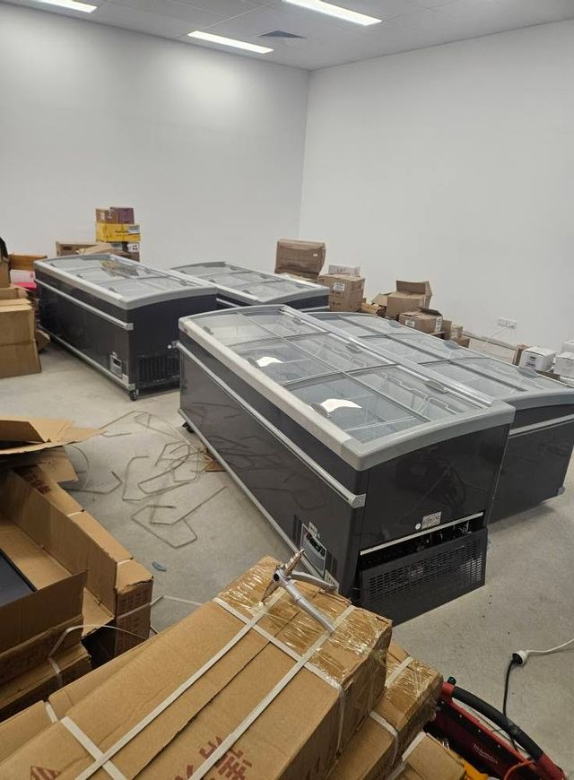 Row of new island display freezers being installed and commissioned in a retail space